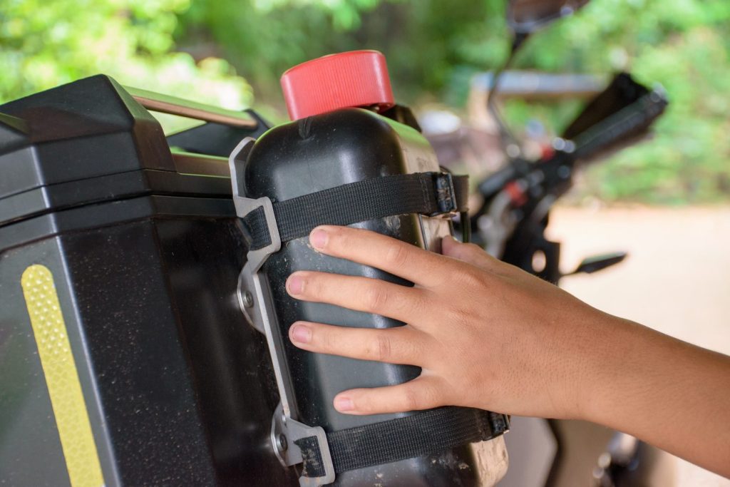 Motard préparant les bagages et les équipements de sa moto avant un road trip.